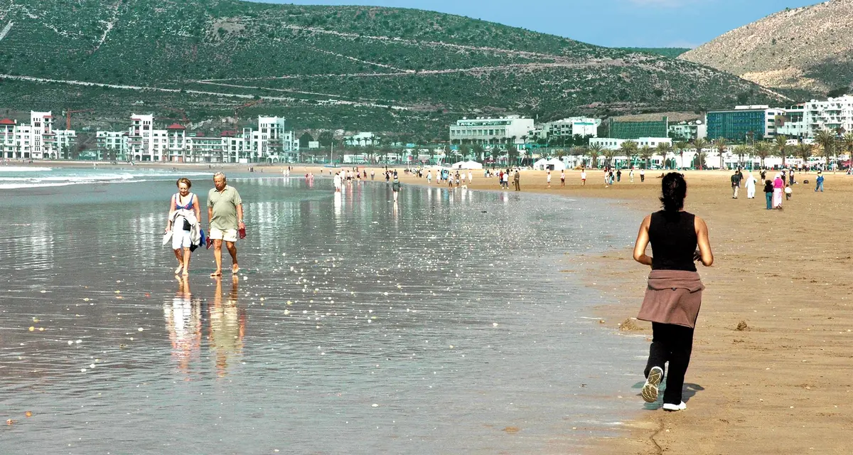 Mensen aan het strand van Agadir met de bergen op de achtergrond