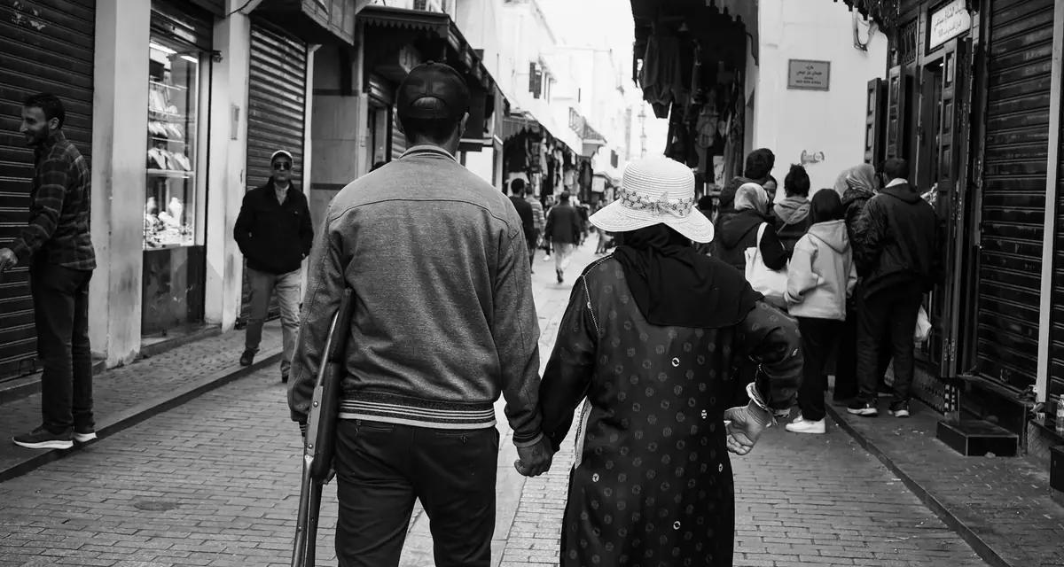 Een ouder echtpaar loopt hand in hand door een straat in Rabat